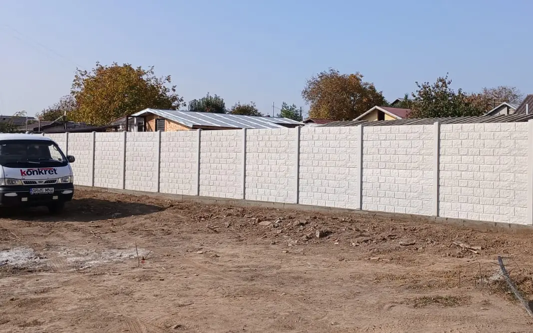 Vozilo kompanije Konkret Line pored bele betonske ograde sa reljefom zidanog kamena